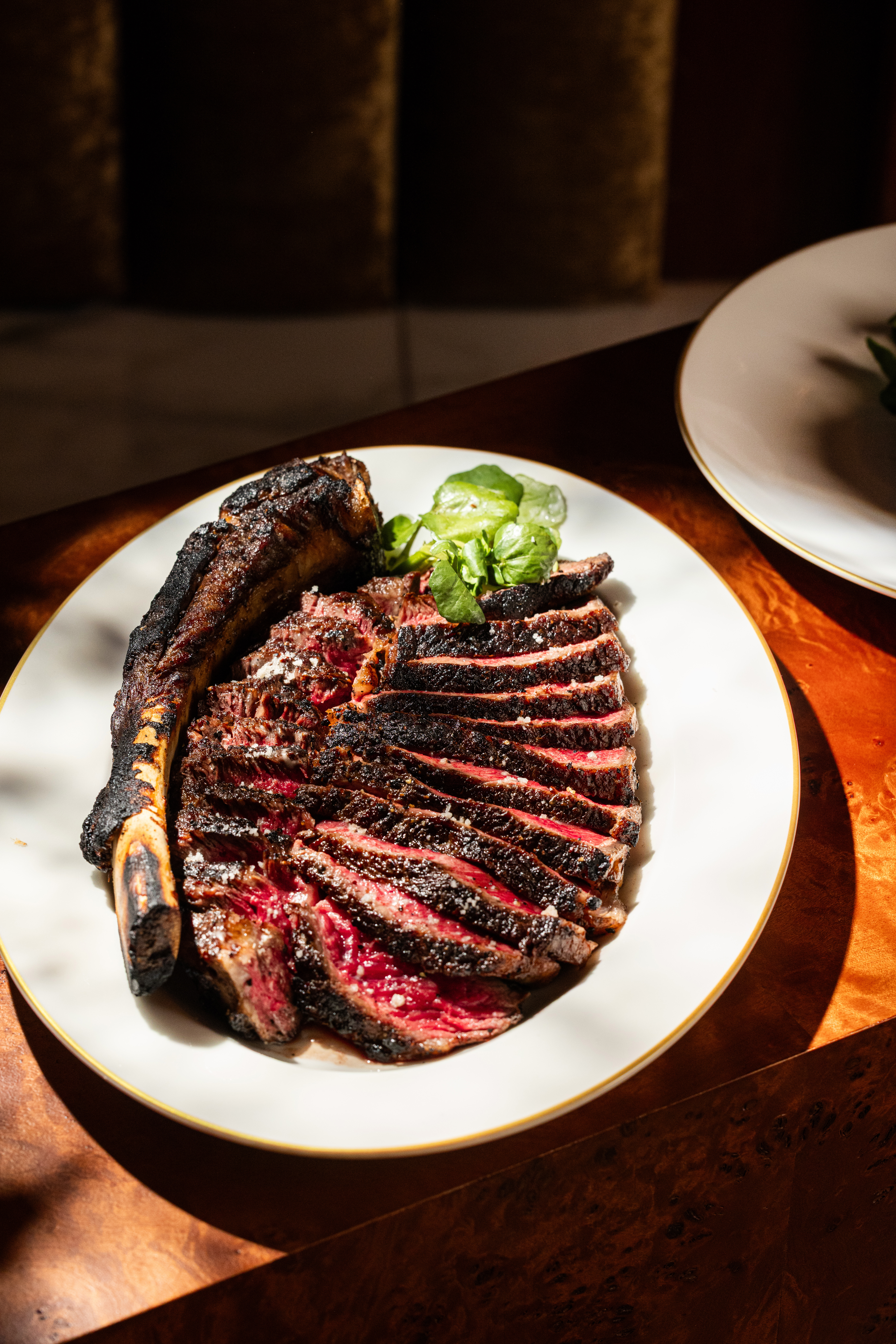 Delilah's signature 32oz tomahawk ribeye, perfectly charred and sliced, served on a gold-rimmed plate