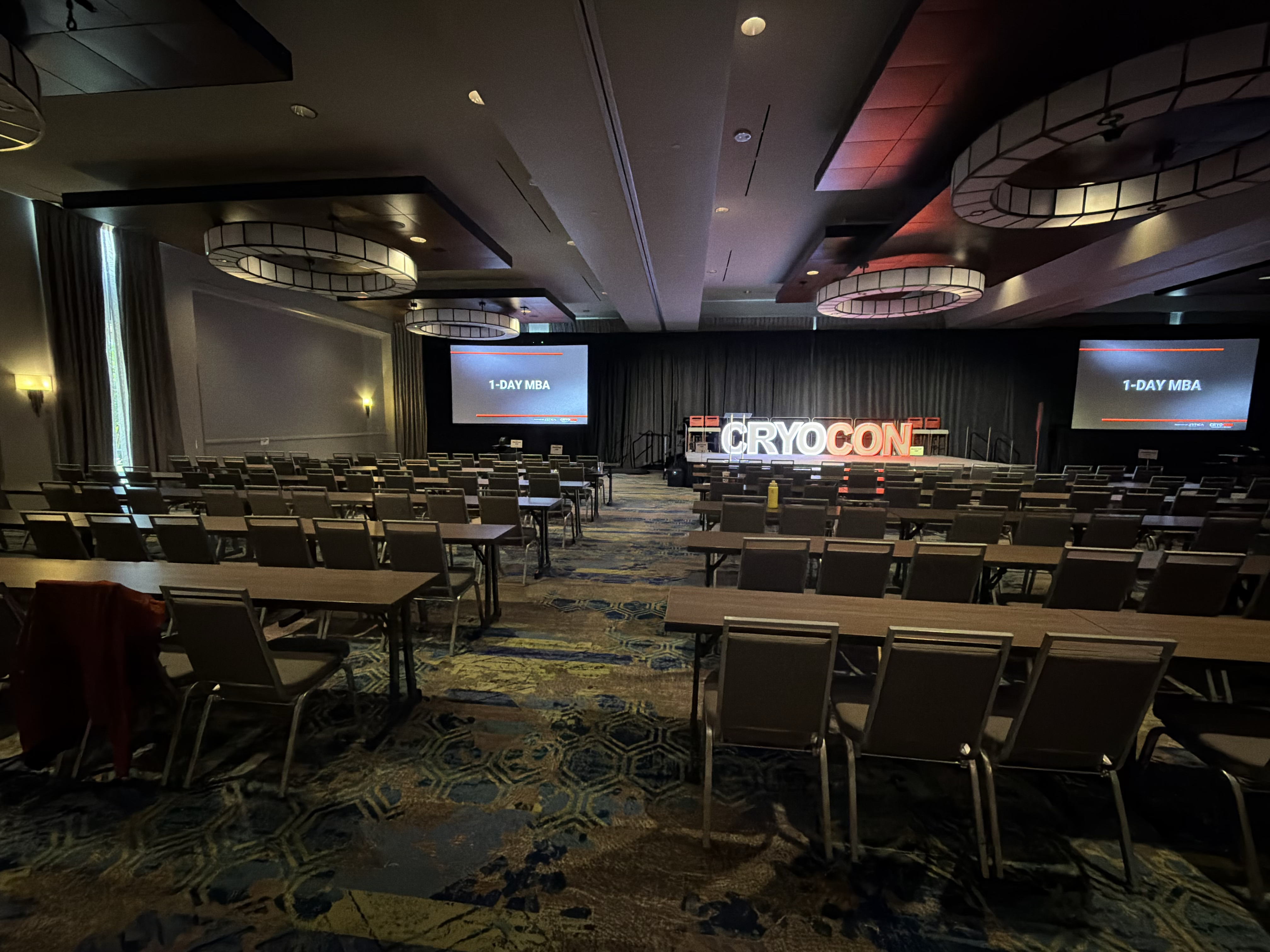 The Appaloosa Room at Embassy Suites Denton set up for CryoCon 2026 with the CryoCon stage and 1-Day MBA screens