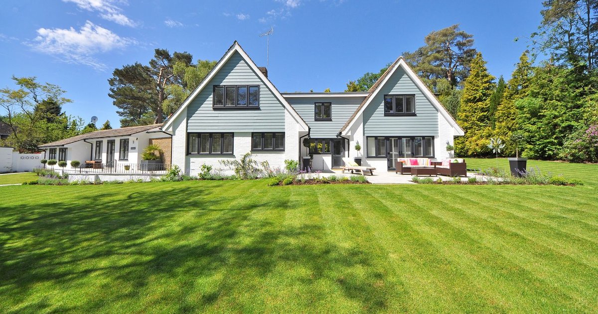 Neat striped green lawn in front of a suburban house under a clear sky
