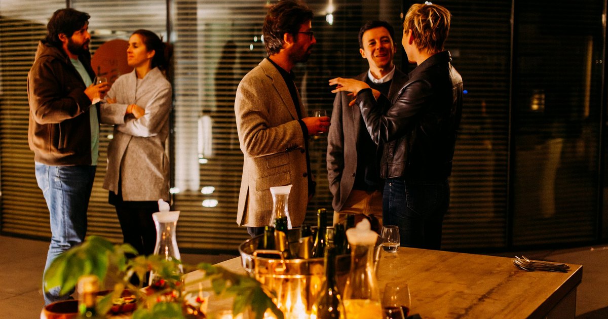 Small groups of adults chatting over drinks at an evening networking get-together