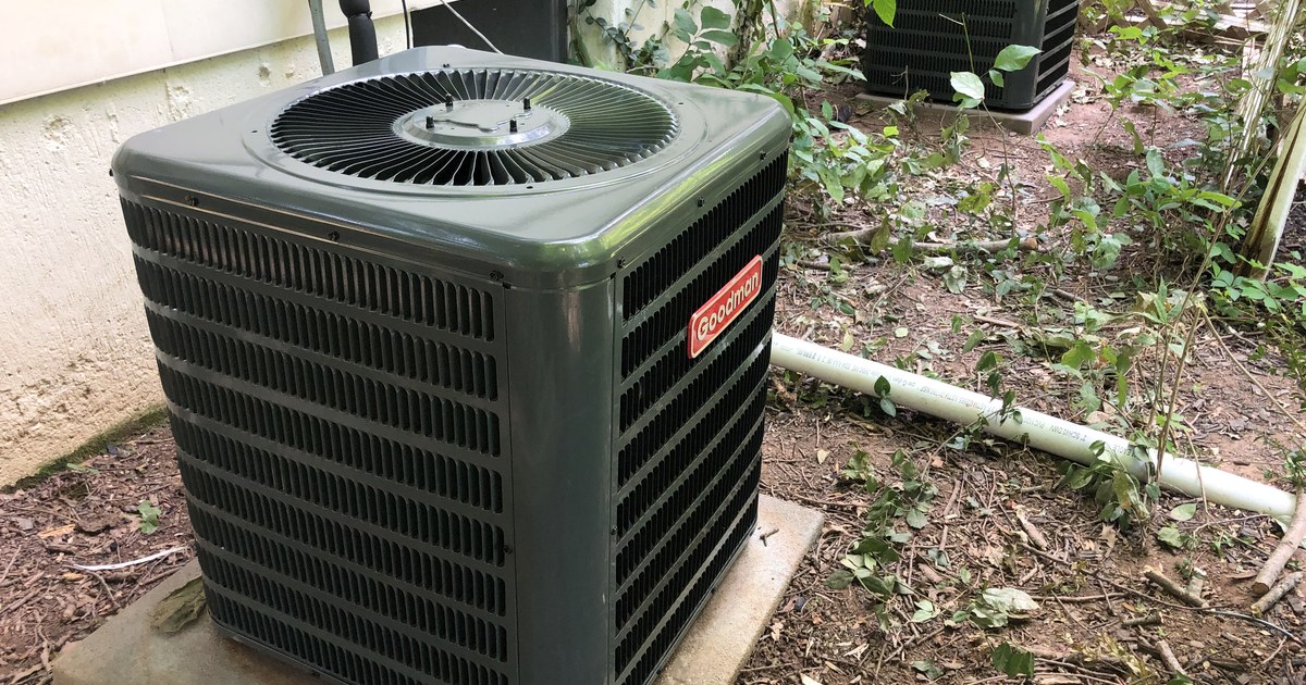 US residential central air conditioner condensers on concrete pads beside a vinyl-sided house